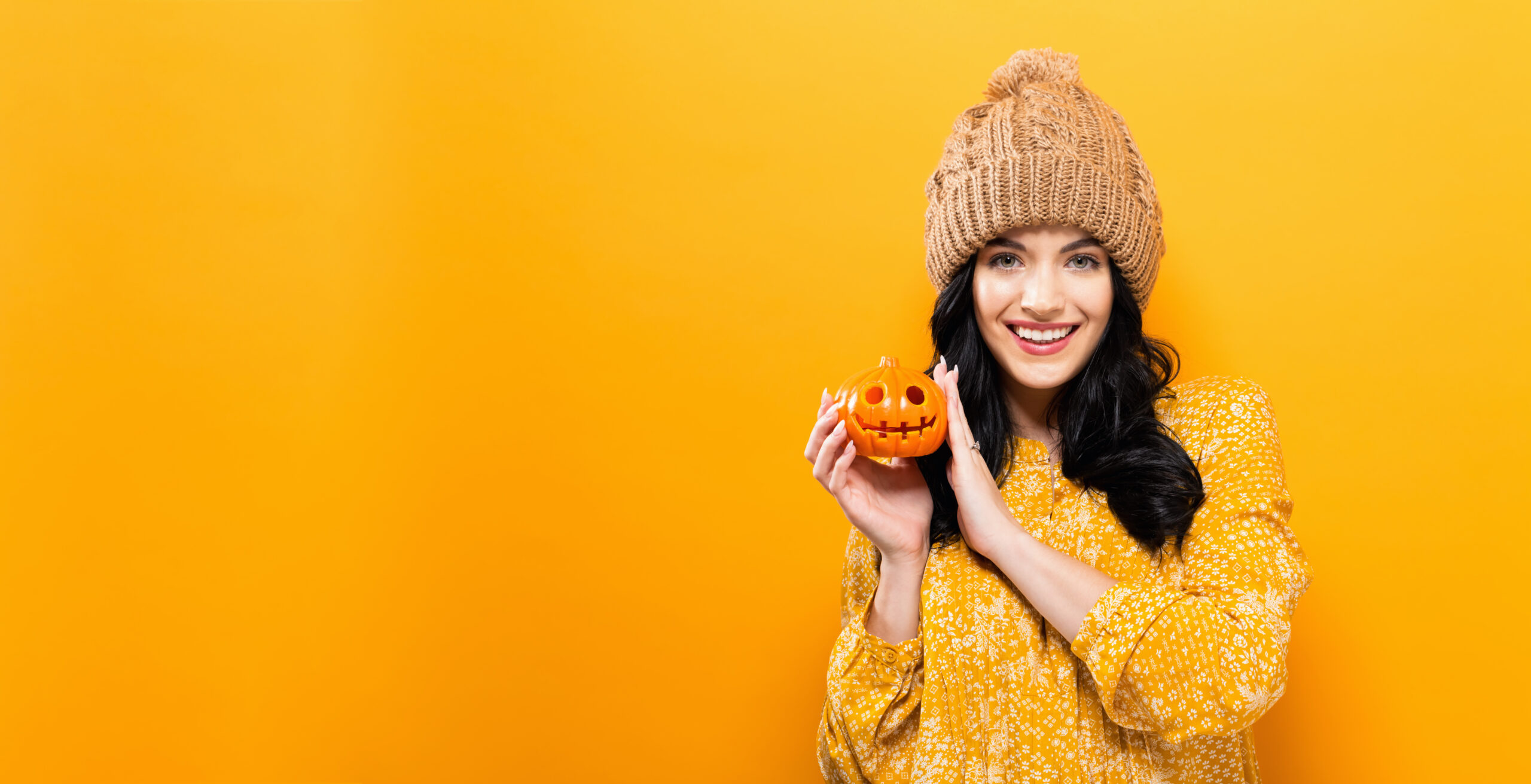 Young woman with a smile holding a pumpkin